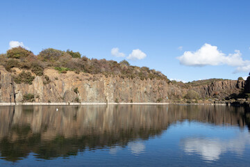 Natural feature: remnants of open quarry created a stunning large water pool. The towering sandstone formations showcase industrial heritage at Prestonhill Quarry, Inverkeithing, Fife, Scotland.

