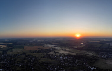 Aerial sunrise above horizon in rural farmlands covered in morning fog