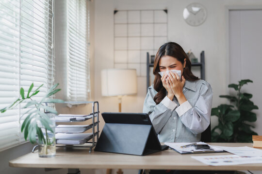 Businesswoman sneezing while working from home office - Powered by Adobe