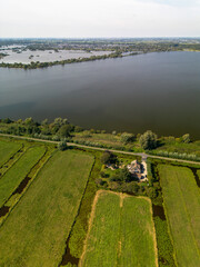Aerial view of rural landscape with irrigated fields, a lakeside house, garden, and distant...