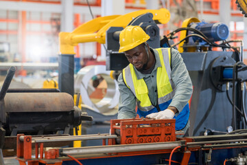 Engineers are working in a steel sheet factory. Technician in safety and helmet suit controlling a machine in factory.