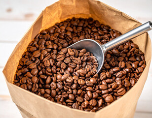 Fototapeta premium A paper bag filled with roasted coffee beans, with a scoop resting in the beans