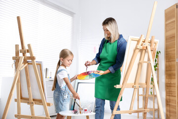 Naklejka premium Choice of profession. Mother teaching her daughter to paint in studio