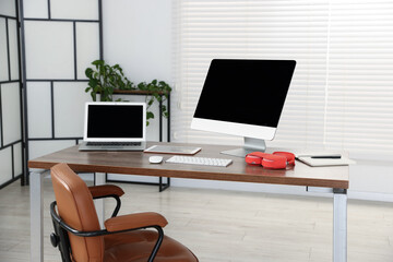Modern workplace with computer, laptop, tablet and headphones on wooden desk in office