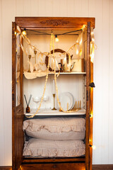 Vintage wooden cabinet filled with decorative items, fairy lights, and soft pillows, creating a cozy atmosphere for home decor enthusiasts and interior design inspiration