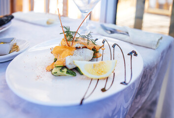 Gourmet seafood dish elegantly plated with grilled fish, fresh vegetables, and lemon slice, garnished with herbs, showcasing culinary artistry and fine dining experience