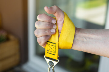Close-up of a hand gripping a yellow strap for armwrestling supination exercise with a weight. Ideal for home training, fitness and strength sport concepts. Focus on forearm, wrist, and grip strength.