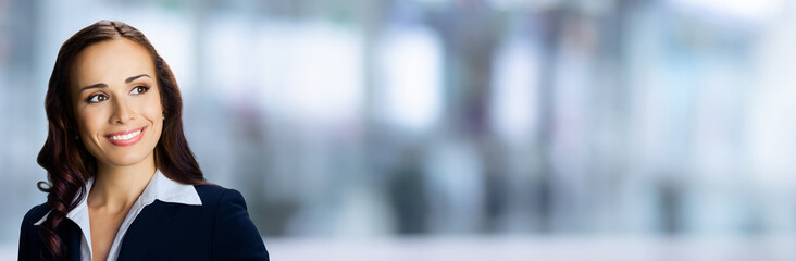 Banner wide image - happy smiling confident cute businesswoman looking gazing upward. Business woman, executive, employee, bank manager, stand against blurred office background with free ad text space
