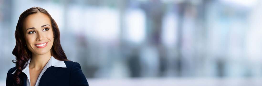Banner wide image - happy smiling confident cute businesswoman looking gazing upward. Business woman, executive, employee, bank manager, stand against blurred office background with free ad text space