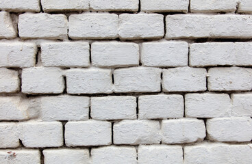 A white brick wall with a few bricks missing