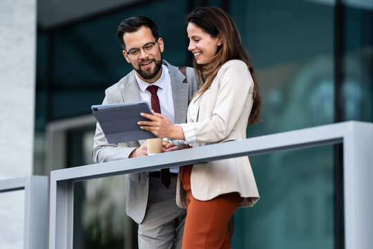 Business people using tablet and drinking coffee outside office building