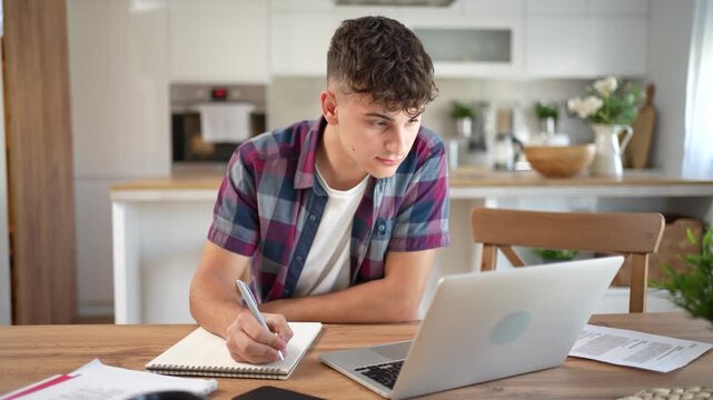 Focused teenager studying online at home using laptop