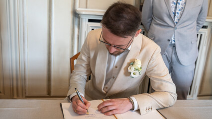 Young male signing marriage papers with beige suite 