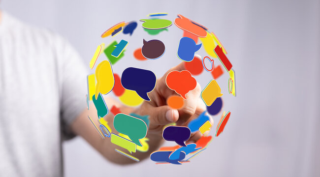 Conceptual shot featuring a hand interacting with a floating globe made of vibrant speech bubbles, symbolizing global connectivity and communica
