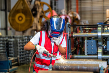Female Welder in a Metal. Woman working in a steel sheet factory. Technician in safety and helmet suit controlling a machine in factory.