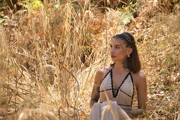 Young, beautiful, Latina woman with tattoos, wearing a white crochet dress, distracted, connected...