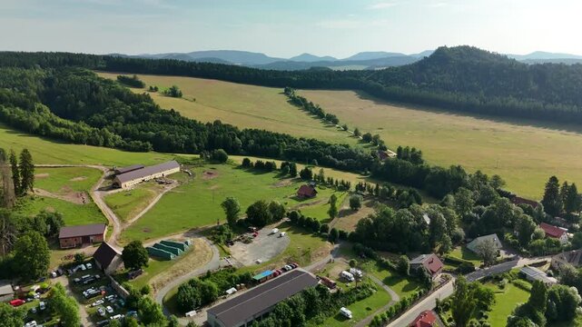 Aerial view of green hills, dense forests, scattered cottages, and winding roads near Teplice Rocks in Adr
