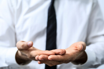 Close-up of businessman in a white shirt and tie, holding out his hands, symbolizing giving, receiving, or offering something, concept and gestu