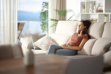 Woman relaxing sitting on a couch contemplating at home