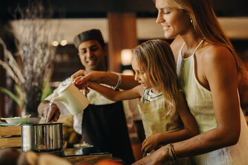 Mother and child cooking together with a chef in a warm kitchen