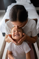 Mother kissing her smiling daughter on forehead