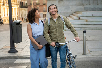 Interracial couple walking city street with bicycle