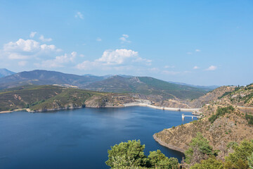 Fototapeta premium Spring panorama with intense green colors on the slopes and turquoise waters of the reservoir on a clear day