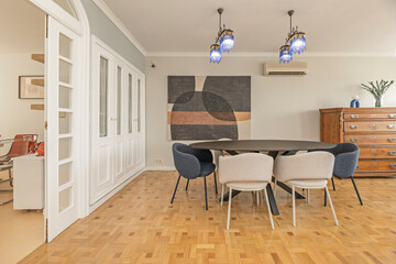 Extendable white dining table with wood details, surrounded by chairs with rattan seats and a lightweight frame