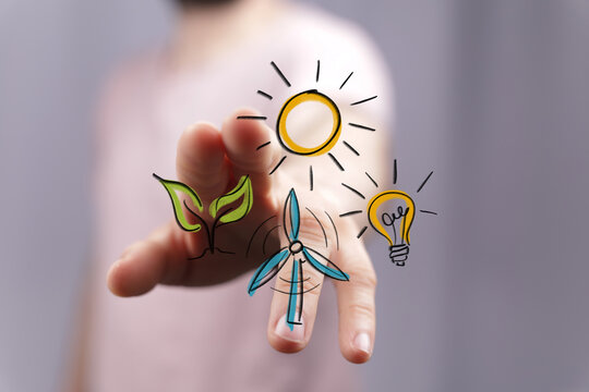 Conceptual hand interacting with digital icons: green leaf, sun, wind turbine, and light bulb. Symbolizes sustainable energy, environmental care