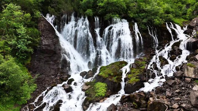 Sibenfalle waterfall in Lenk, Switzerland multiple cascades tumbling over mossy rocks into clear pools amid lush alpine forest, showcasing raw mountain power and pristine nature, static shot