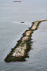 Aerial view of a man-made dike in Venice, Italy, designed for coastal protection and navigation, creating a path in the middle of the sea.