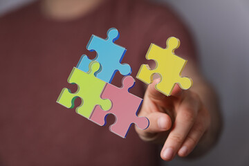 Hand assembling a jigsaw puzzle. Concept of teamwork, problem solving, unity, and coming together. Represents strategy, creativity, and innovati