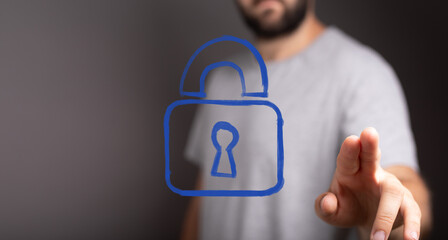 A man's hand reaches out to touch a virtual padlock icon, symbolizing digital security, data...