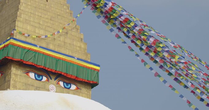 Close-up of Boudhanath Stupa, Kathmandu, Nepal. Buddhist prayer flags flow gently in the sunny sky as Buddha eyes gaze peacefully, radiating spiritual vibes and sacred cultural heritage