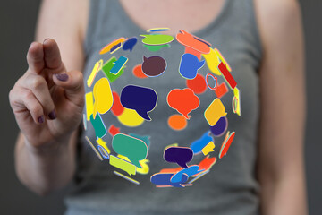 A hand interacts with a spherical arrangement of speech bubbles, representing communication and...