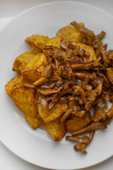 Delicious oven baked potatoes with chanterelle mushrooms served on a white plate. Top down food shot for recipe blogs, cooking magazines, or restaurant menus. Rustic comfort food at its best.