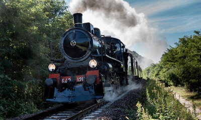 Vintage steam train runs on the tracks in the countryside