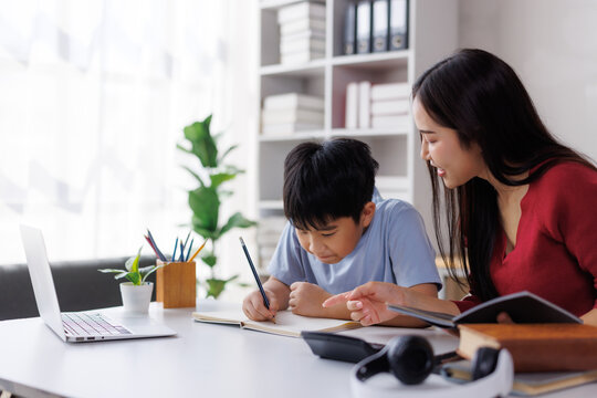 Asian mother helping son with homework at home
