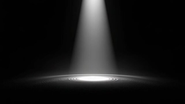 A single spotlight shines on a dark stage, illuminating a bright circular patch on the floor.
