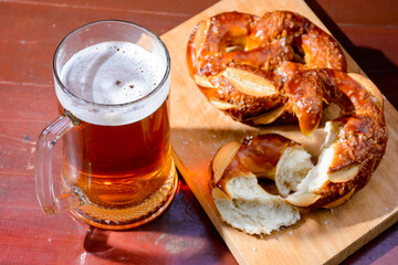 beer and pretzel on the table. celebration of oktoberfest. glass mug with cold beverage and baked salt snacks on the wooden background. rustic scene