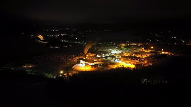 Panoramic drone shot circling a wood processing facility, night in East Finland