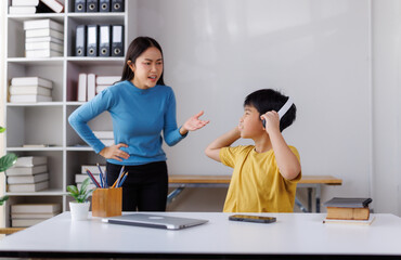 Asian mother scolding son listening music with headphones at home