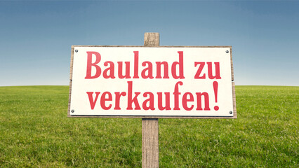 Schild auf der grünen Wiese: Bauland zu verkaufen!