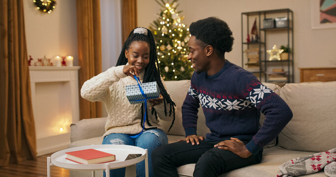 On Christmas Eve, two friends of multi-ethnic background sit on a couch. The young man gives a gift to the young woman, who unpacks the box and is infinitely happy with the surprise. She smiles and