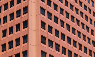 A high building with a large number of windows. The office building of the red-brick color (terracotta) is perfect as texture, background or design. Horizontal photo