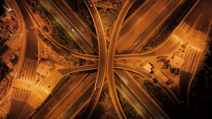 Aerial drone slow shutter night shot of illuminated multilevel junction motorway with light traffic...