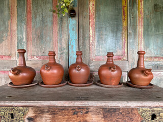 Close up of handcraft clay jug display on a wooden cabinet. Clay teapot or drinking jug is a traditional drink pitcher at old times. Vintage and retro concept display. Traditional and rural vibes. 