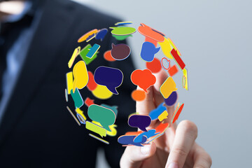 A person touches a globe of floating speech bubbles, symbolizing global communication and digital...