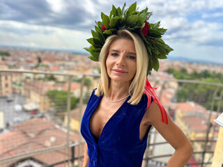 Proud graduate girl celebrating academic success with laurel garland near Pisa Tower landmark