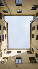 Yellow courtyard well in old residential house from historical center of Riga, Latvia. Cloudy blue sky. The facade with many windows. Travel destination concept. Copy space